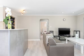 A modern living room with a sofa, TV, and a dining area. - Ravens 9A (Cape Town)