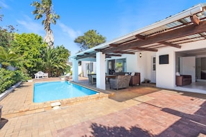 A pool with a patio area, outdoor furniture, and a covered seating area. - Ravens 9A (Cape Town)