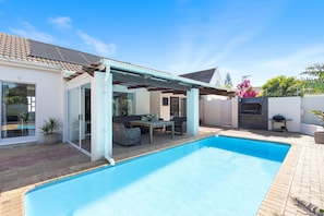 A backyard with a swimming pool, a covered patio, and a barbecue area. - Ravens 9A (Cape Town)