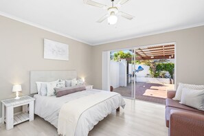 A bedroom with a bed, bedside table, lamp, and a ceiling fan.