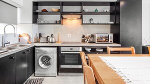 A modern kitchen with built-in appliances, a dining area with a table and chairs, and a washing machine. - Cozumel 308 (eMdloti)