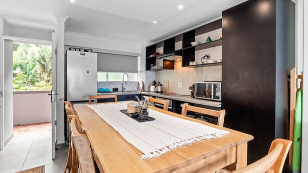 A modern kitchen with a wooden dining table, built-in cabinets, and a black accent wall. - Cozumel 308 (eMdloti)