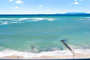 A beach with clear turquoise water, a sandy shore, and a pier extending into the sea. - Odeon Towers 1007 (Cape Town)
