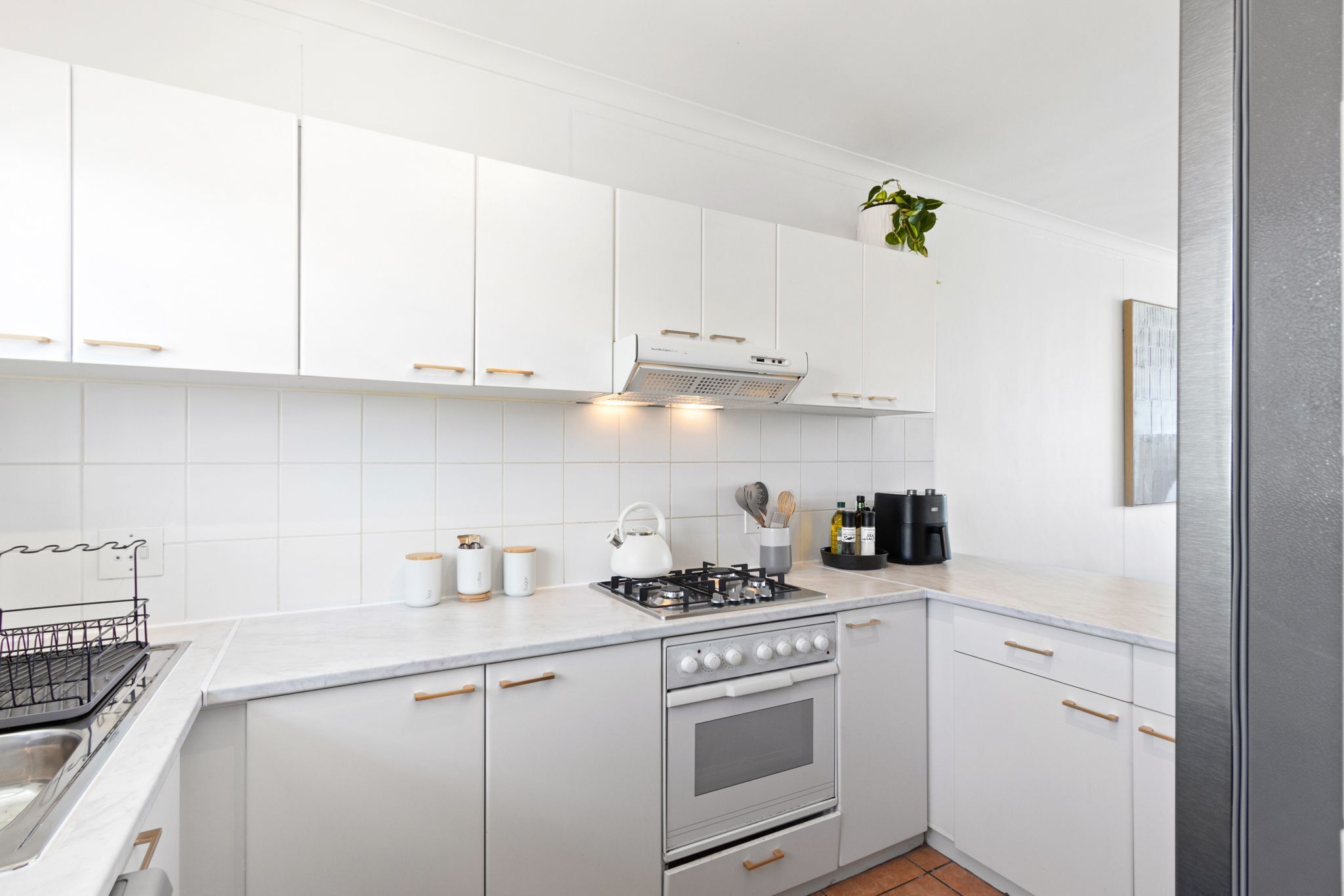 Une cuisine moderne avec des armoires blanches, une cuisinière en acier inoxydable et un four encastré.