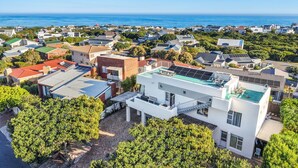 Un quartier résidentiel avec des maisons modernes, une piscine sur le toit et une vue sur l’océan.