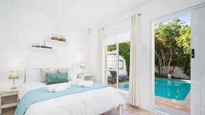 Une chambre à coucher avec un lit, des tables de chevet, une lampe et une vue sur une piscine.