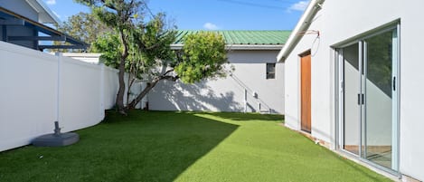 Une maison moderne avec une façade blanche, un toit végétalisé et une pelouse bien entretenue.