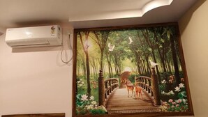 Un murale raffigura una scena di bosco con un ponte e cervi, un condizionatore d'aria a parete e un soffitto con un faretto incassato.