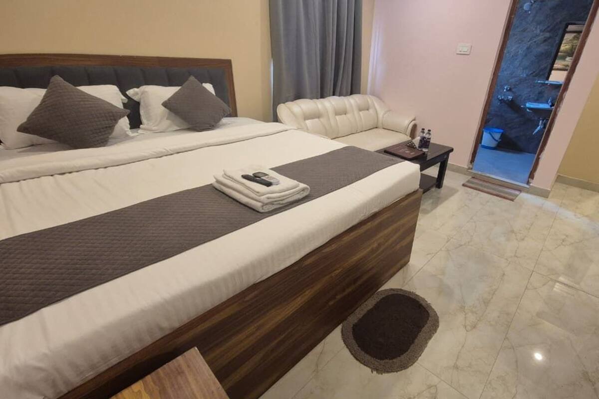 A hotel room with a large bed, a bedside table, a chair, and a bathroom visible through an open door.
