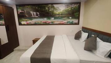 A bedroom with a bed, a nightstand, a wall-mounted TV, and a large mural of a waterfall and lotus flowers.