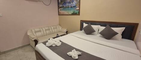 A hotel room with a bed, a sofa, and a painting of a beach scene.