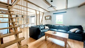 A living room with a black leather sofa, wooden coffee table, and a staircase with wooden railings. - Stunning home in Zutkerque with WiFi (Zutkerque)