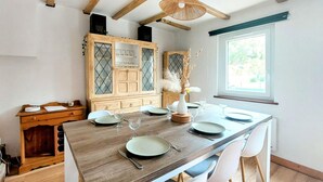 A dining area with a wooden table set for four, surrounded by white chairs. A cabinet with glass doors is visible in the background. - Stunning home in Zutkerque with WiFi (Zutkerque)
