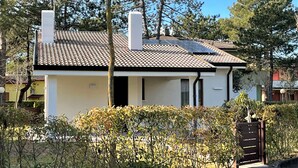 Una casa de dos pisos con techo de tejas, una chimenea y un acceso con portón.