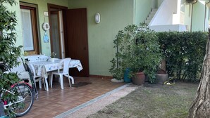 Un'area patio con tavolo e sedie, una bicicletta e una pianta in vaso.
