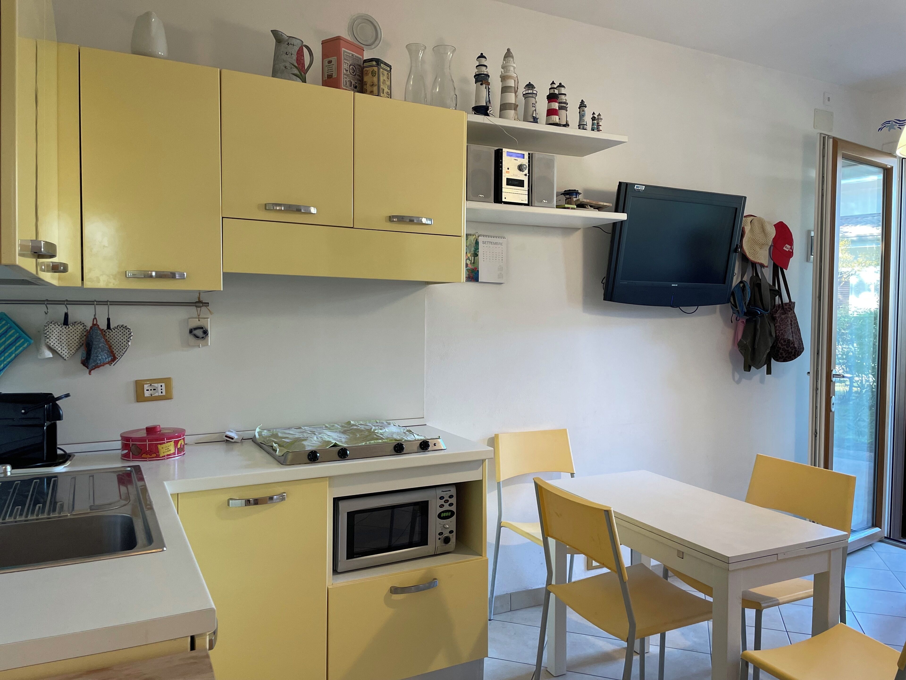 Une cuisine compacte avec des meubles de couleur jaune, un four à micro-ondes, une cuisinière et un coin repas comprenant une table et des chaises.