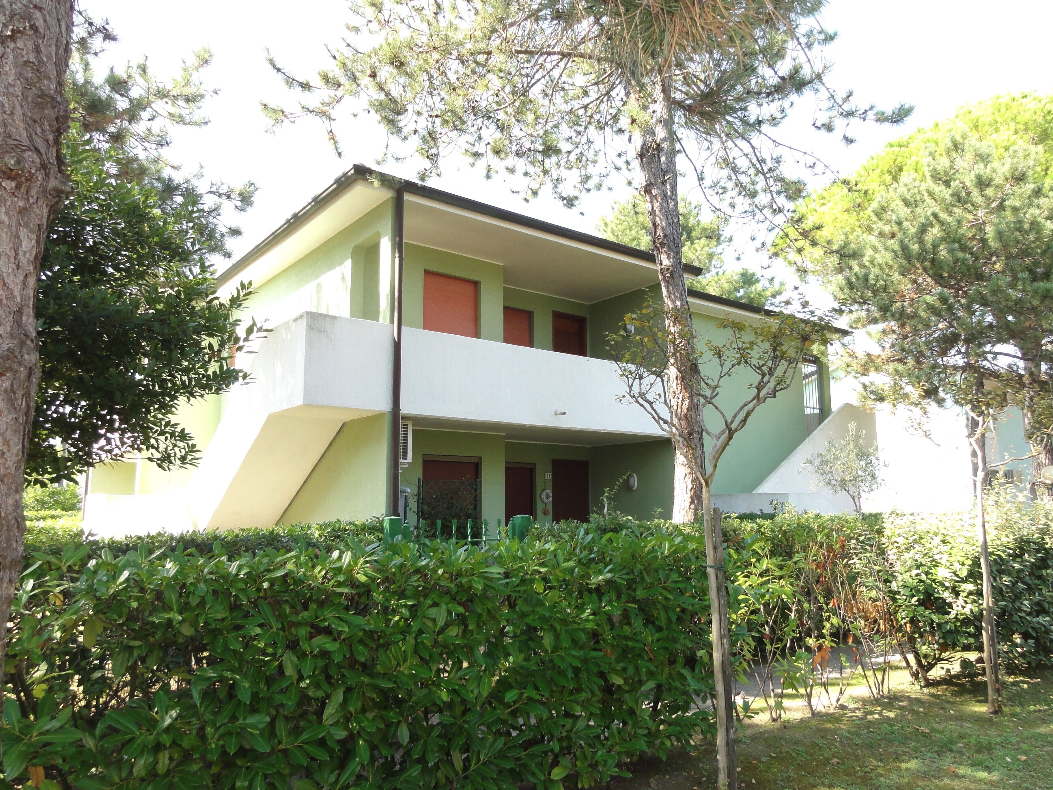 Un bâtiment à deux étages, doté d’un toit plat et entouré de verdure et d’arbres.
