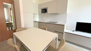 Una cucina moderna con zona pranzo, comprensiva di tavolo e sedie, forno a microonde e TV a schermo piatto.