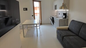 A modern kitchen with a dining area, a sofa, and a flat-screen TV. - Very comfortable seafront apartment (Bibione)