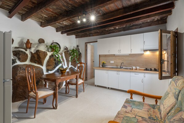 A kitchen with white cabinets, a dining table with chairs, and a sofa.