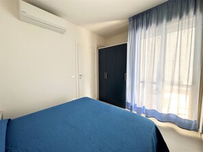 A bedroom with a bed, a wardrobe, and a window with curtains.