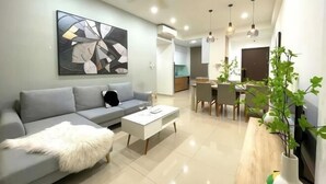 A modern living room with a grey sofa, a white coffee table, and a large abstract painting on the wall. - Solina Home Sun Anvenue Apartment (Ho Chi Minh City)