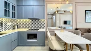 A modern kitchen with grey cabinets, a patterned backsplash, and a dining area with a marble table and chairs. - Solina Home Sun Anvenue Apartment (Ho Chi Minh City)