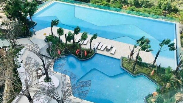 A swimming pool with a modern design, surrounded by palm trees and lounge chairs. - Solina Home Sun Anvenue Apartment (Ho Chi Minh City)