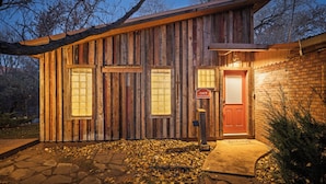 A rustic wooden cabin with a brick exterior, a red door, and a sign indicating 'Unit B'. - Creekside Cowa-Bungalow | Moab Studio w/ Soaking Tub (Moab)