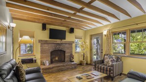 Una sala de estar acogedora con chimenea, sofás de cuero, una mesa de centro de madera y ventanas amplias.