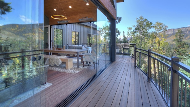 A modern cabin with a wooden deck, large windows, and a view of the surrounding forest. - Brand New Home on 2 Acres - Amazing Deck/Views - Hot Tub/BBQ/Fire Table/AC (Durango)
