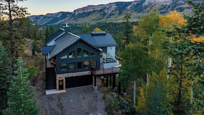 A modern house with a large garage, a deck, and a mountain backdrop. - Brand New Home on 2 Acres - Amazing Deck/Views - Hot Tub/BBQ/Fire Table/AC (Durango)