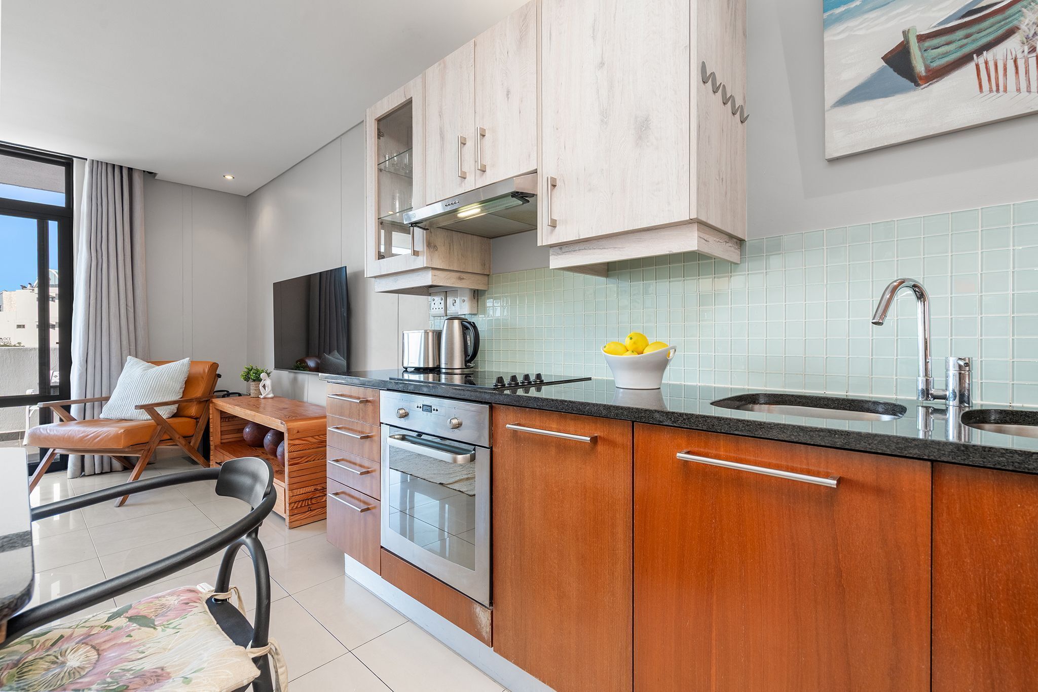 A modern kitchen with wooden cabinets, a built-in oven, and a large window.