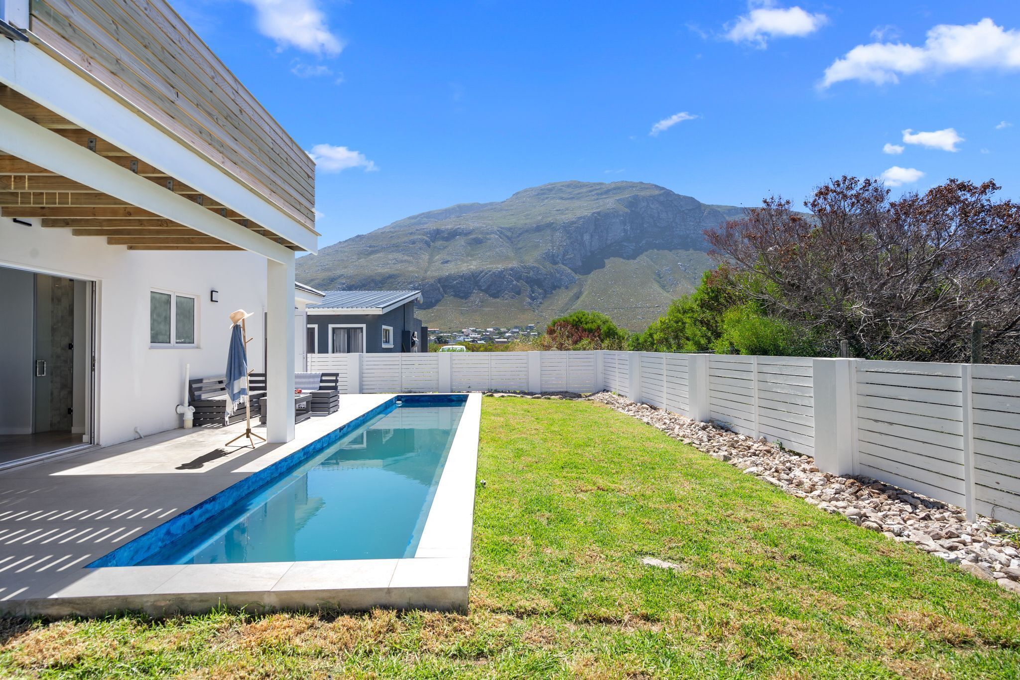 A modern house with a swimming pool, a patio, and a view of a mountain.