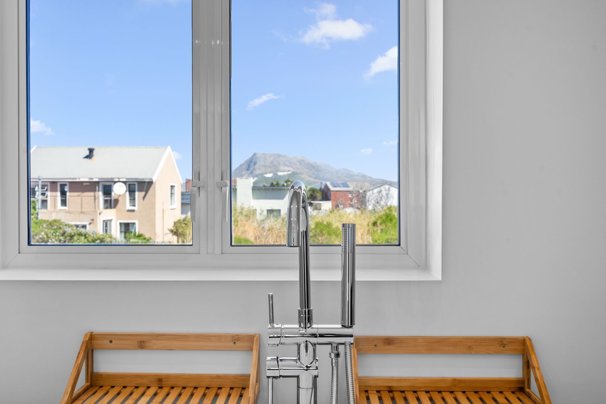 A bathroom with a shower and a view of a mountain through a window.