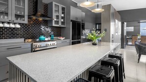 A modern kitchen with a large island, stainless steel appliances, and a black and white backsplash. - Red River Valley (Rooiels)