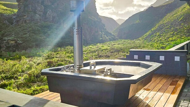 A hot tub on a wooden deck with a mountainous backdrop. - Red River Valley (Rooiels)
