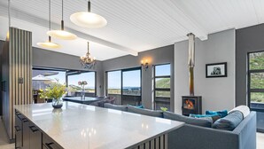 A modern kitchen with a large island, pendant lighting, and a view of the outdoors. - Red River Valley (Rooiels)