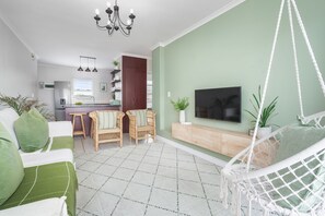 A living room with a sofa, two chairs, a TV, and a hanging chair. - The Sands BG3 (Cape Town)