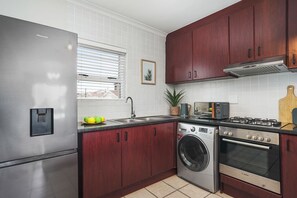 Une cuisine moderne dotée d’appareils électroménagers en acier inoxydable, de meubles en bois et d’une fenêtre avec des stores.