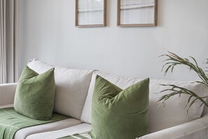 A white sofa with green cushions and a plant beside it. - The Sands BG3 (Cape Town)