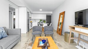 A modern living room with a sofa, two armchairs, a coffee table, and a TV on a wooden stand. - Beach Break 47 (Cape Town)