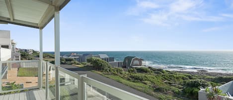 A balcony with a view of the ocean and coastal buildings.