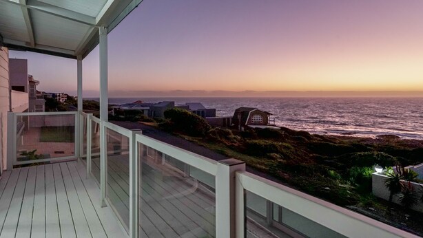 A balcony with a view of the ocean at sunset.