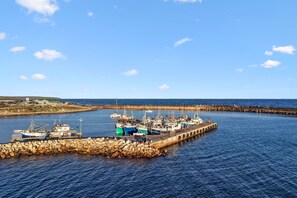 A harbor with multiple boats docked at a stone pier. - The Tides at Gansbaai (De Kelders)