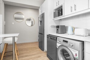 A modern kitchen with white cabinets, a dishwasher, a microwave, and a coffee maker.
