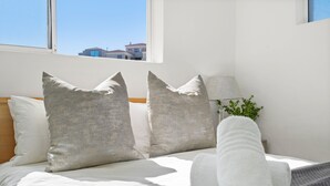 A neatly made bed with pillows, a rolled towel, and a lamp on a nightstand. - Balmoral Heights 20 (Cape Town)