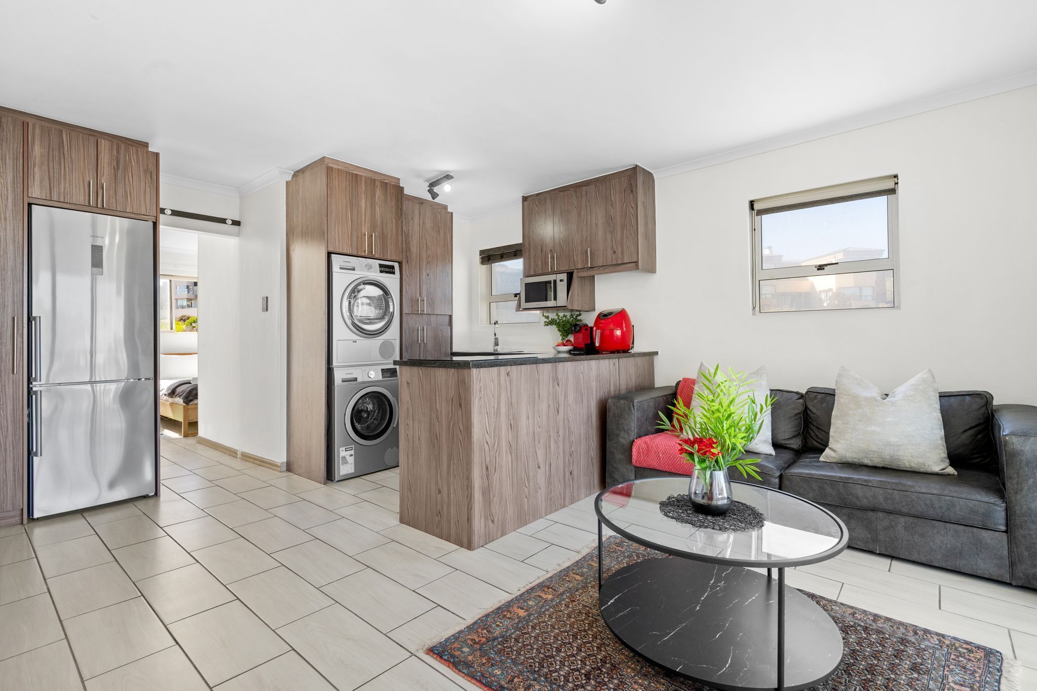 A modern kitchen with wooden cabinets, a built-in washing machine, and a red appliance.