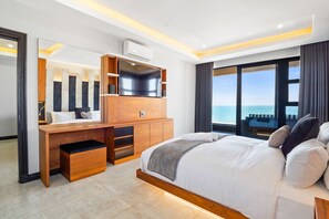 Una habitación de hotel moderna con una cama grande, un escritorio de madera, un espejo y vistas al mar.