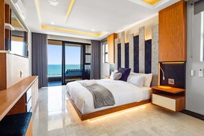Un dormitorio moderno con una cama grande, una mesita de noche de madera, un estante empotrado y vistas al océano.